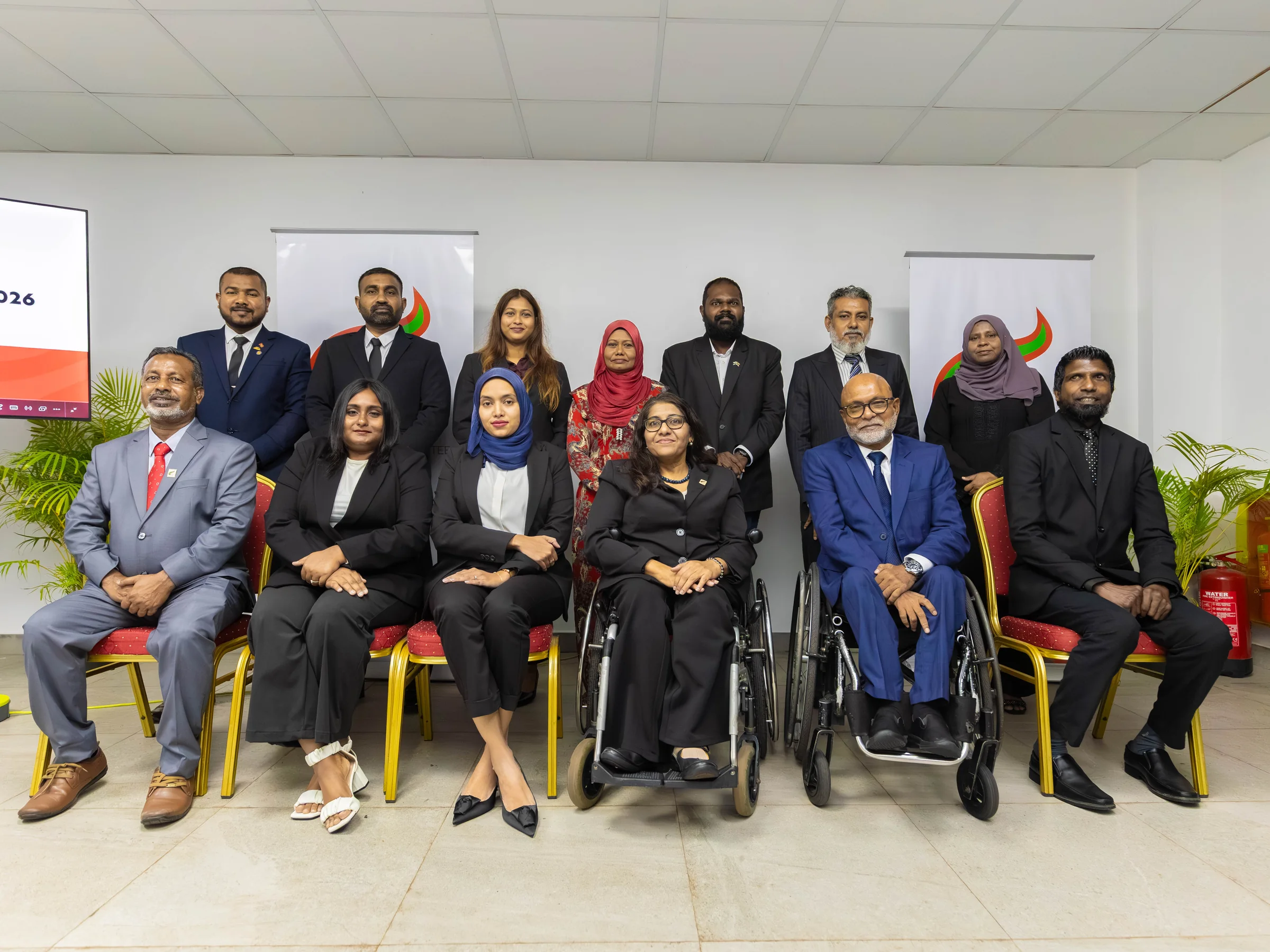 AGM participants pose together in two rows in the meeting room.